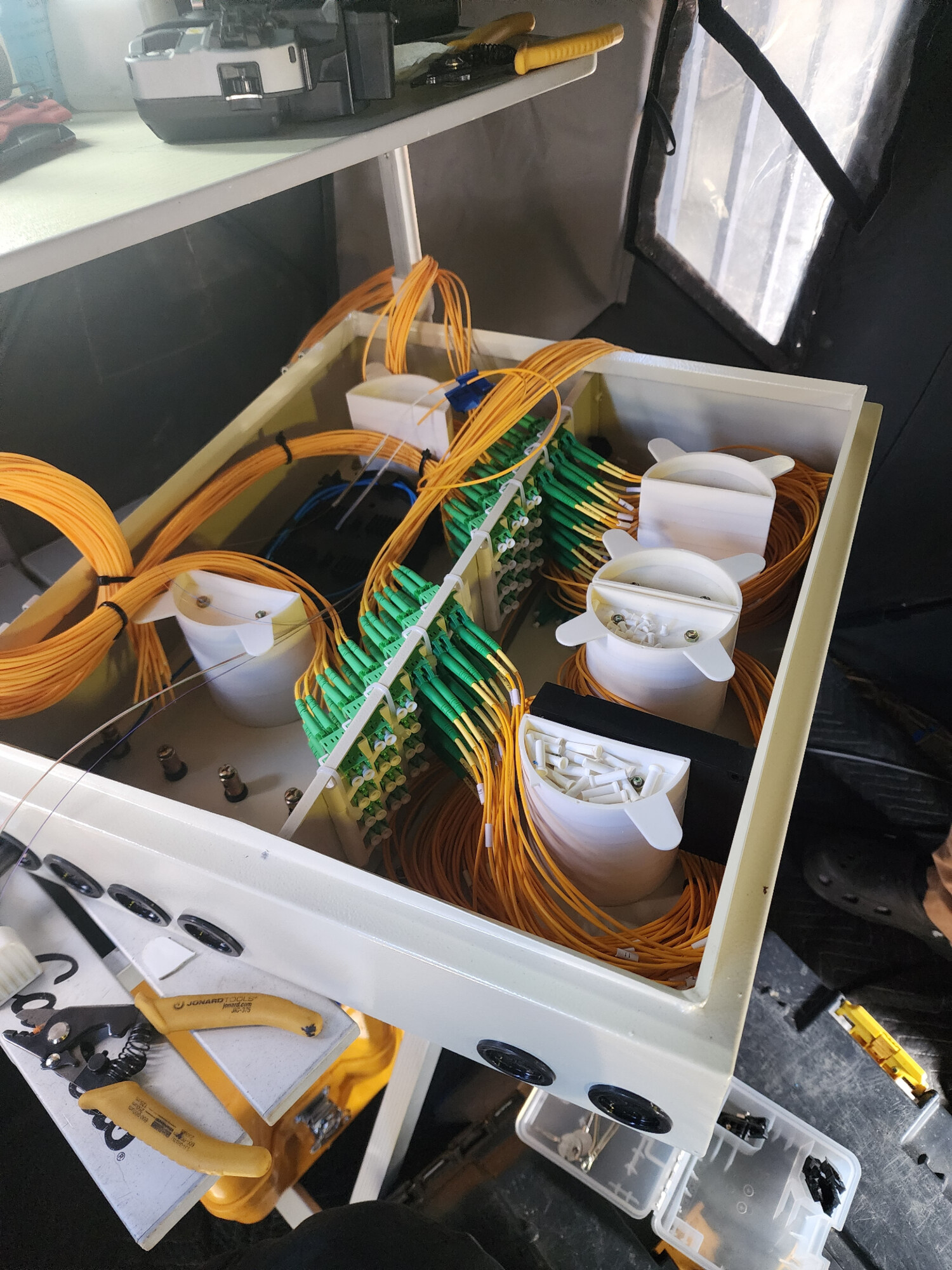 Technician splicing fiber optic strands inside a network cabinet